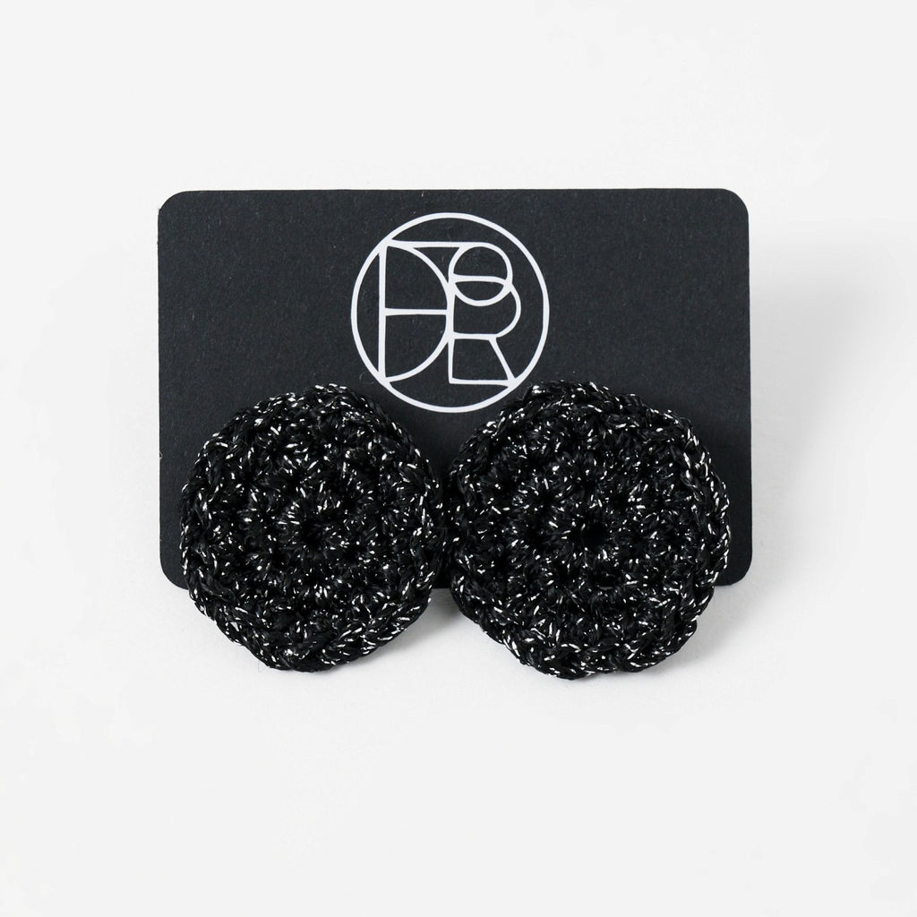 The Vela crochet disc earrings in midnight black with silver shimmer, styled display - Lodorfo