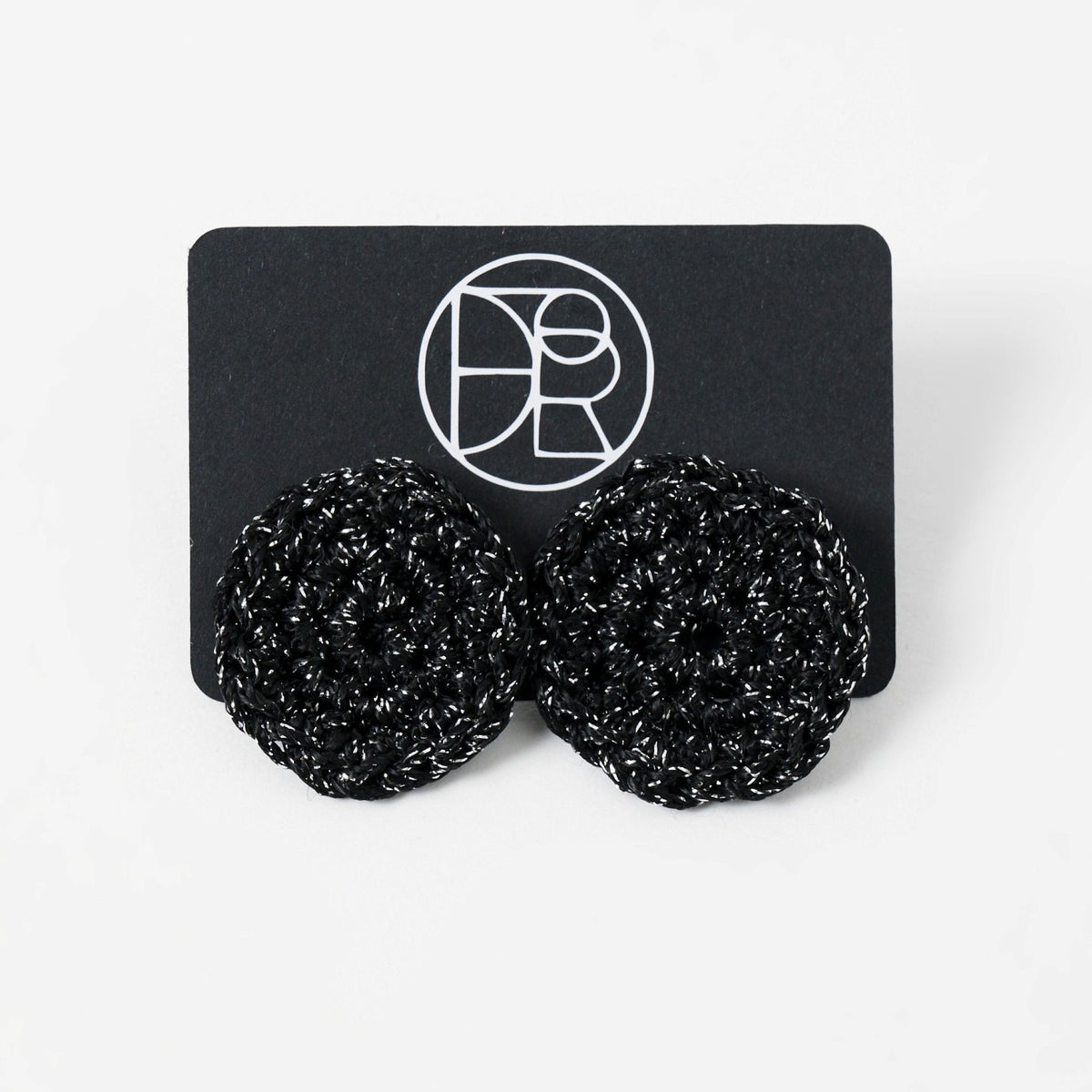 The Vela crochet disc earrings in midnight black with silver shimmer, styled display - Lodorfo