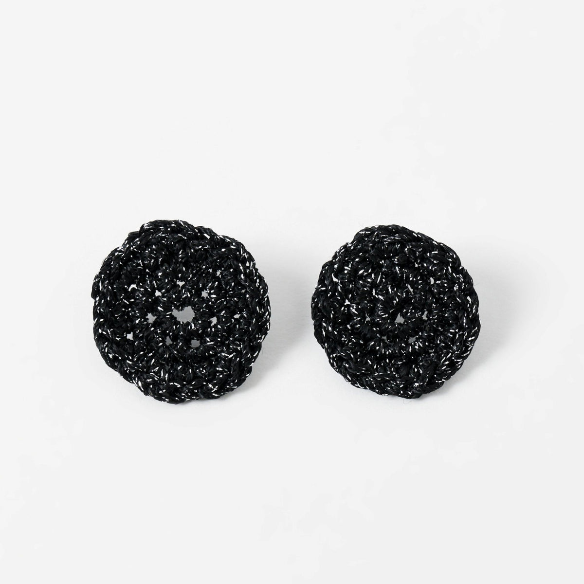 The Vela crochet disc earrings in midnight black with silver shimmer, flat lay - Lodorfo