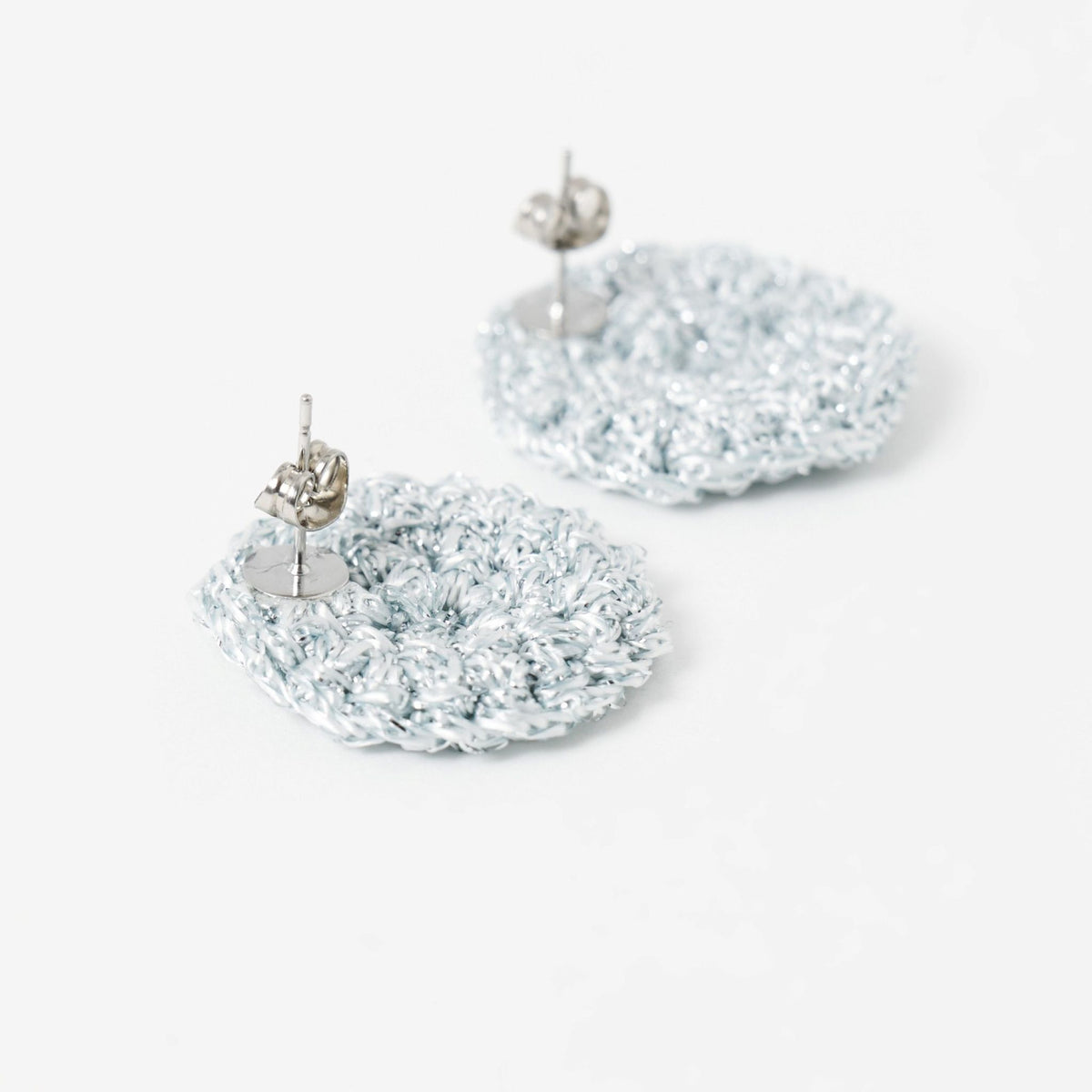 Close-up of the hand-crocheted texture of the Vela disc earrings in pebble grey with silver shimmer - Lodorfo
