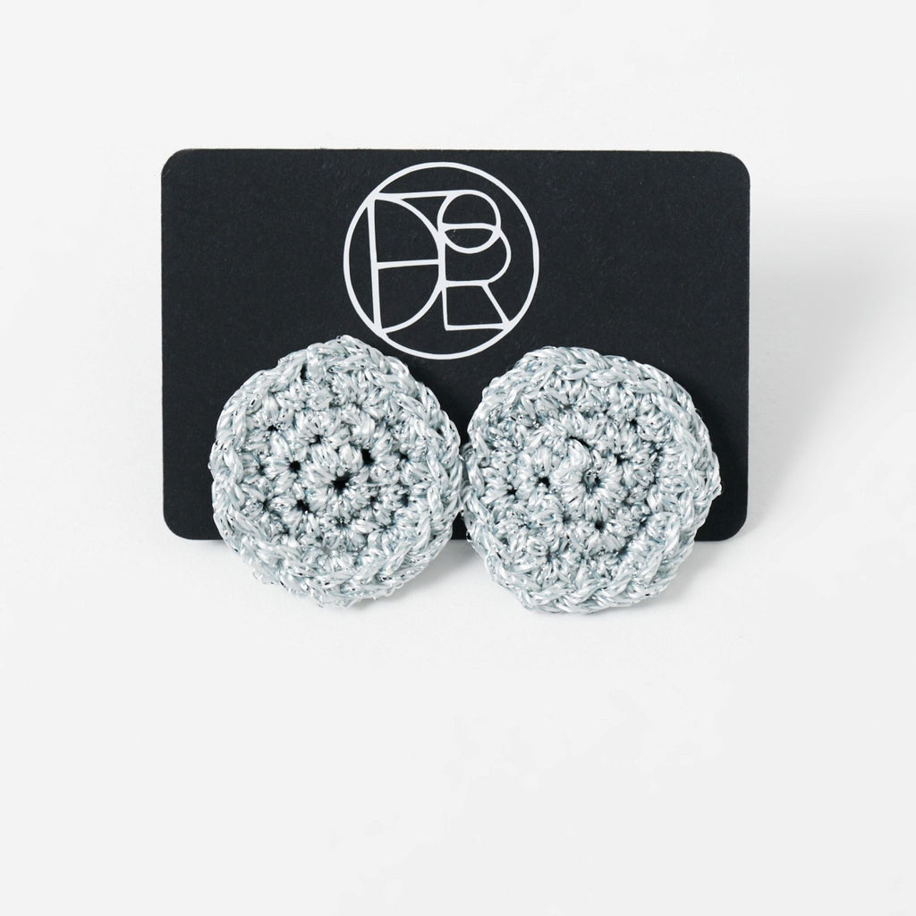 The Vela crochet disc earrings in pebble grey with silver shimmer, styled display - Lodorfo