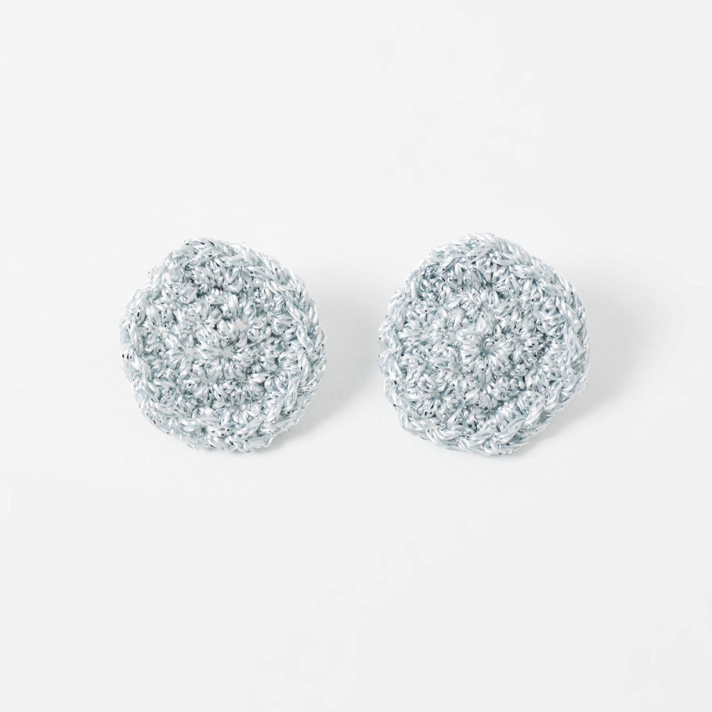 The Vela crochet disc earrings in pebble grey with silver shimmer, flat lay - Lodorfo