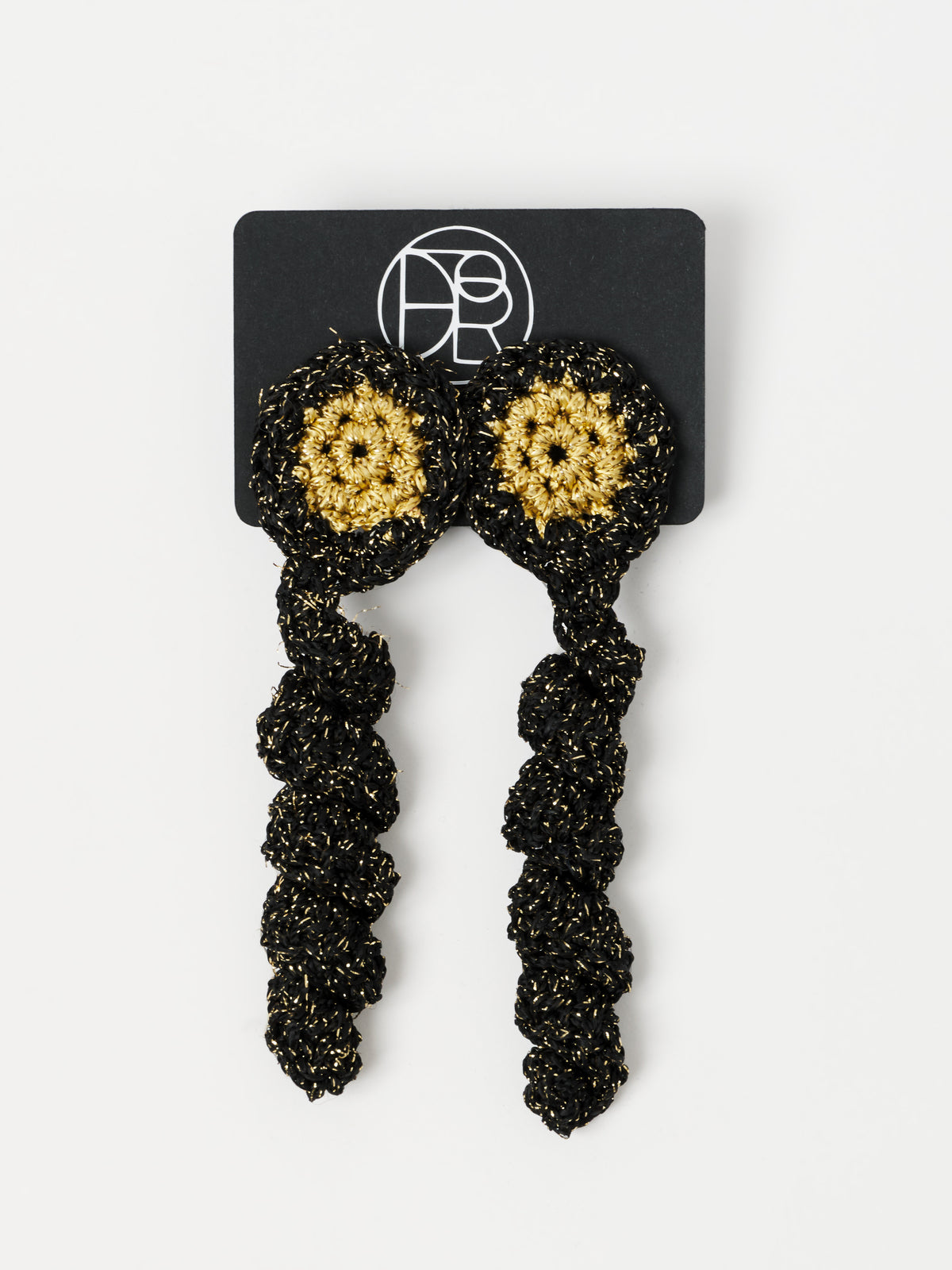 A pair of long, chunky black beaded dangle earrings with gold circular stud details, displayed on a black branded card against a light gray background.