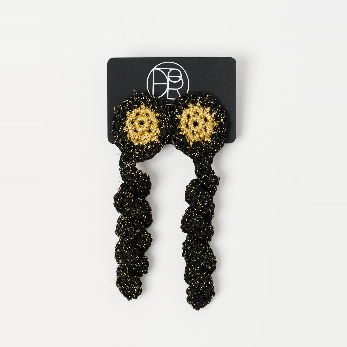 The Noire crochet drop earrings with a gold centre, on a Lodorfo presentation card - Lodorfo