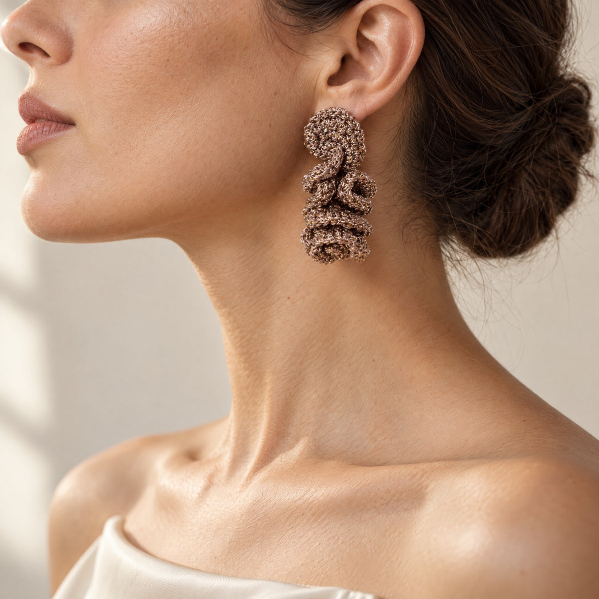 Woman wearing the Elara fawn crochet spiral drop earring with silver shimmer, handmade UK - Lodorfo