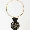 Statement geometric pendant necklace featuring a bold black and gold textured medallion suspended from a sleek gold choker.