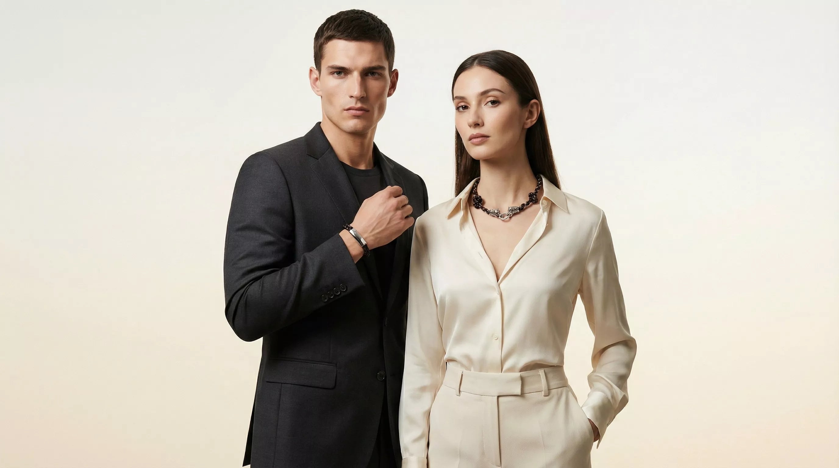 Man and woman in formal attire standing side by side against a plain background