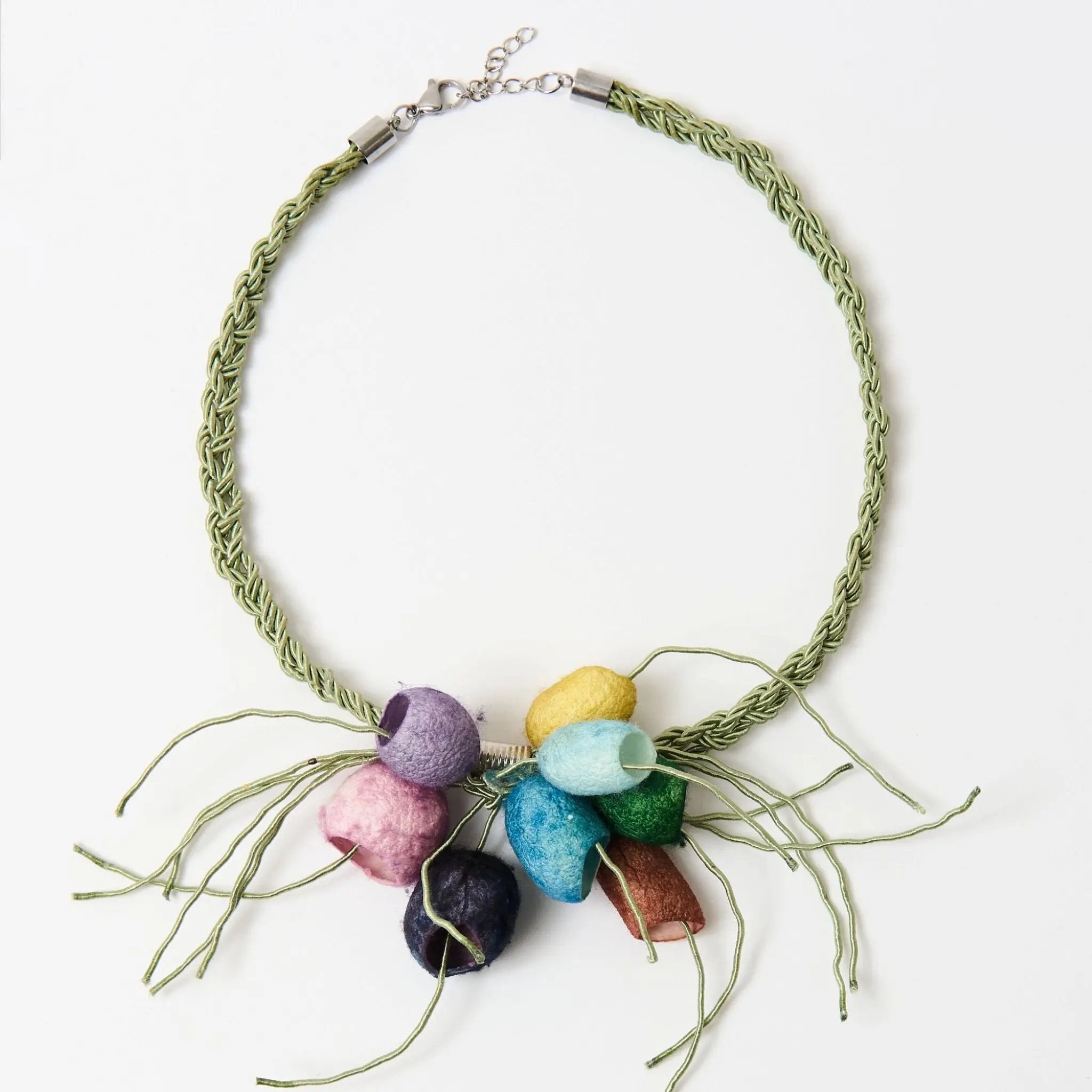 Handcrafted statement necklace featuring a braided green cord with a cluster of silk cocoons secured with a metal clasp. Shown on a white background.
