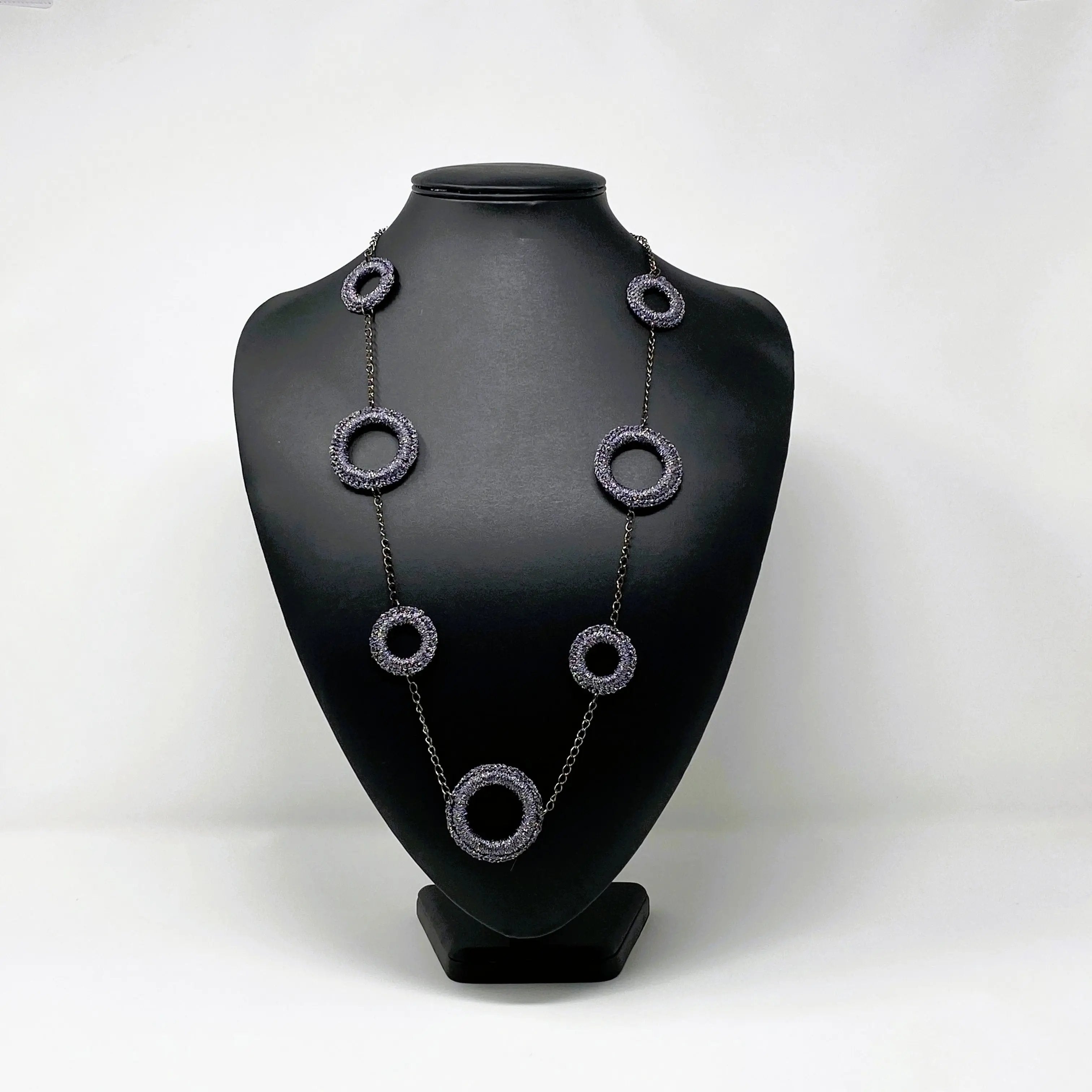 Charcoal ring necklace elegantly draped on a black display bust, showcasing its modern circular design and metallic chain detailing.