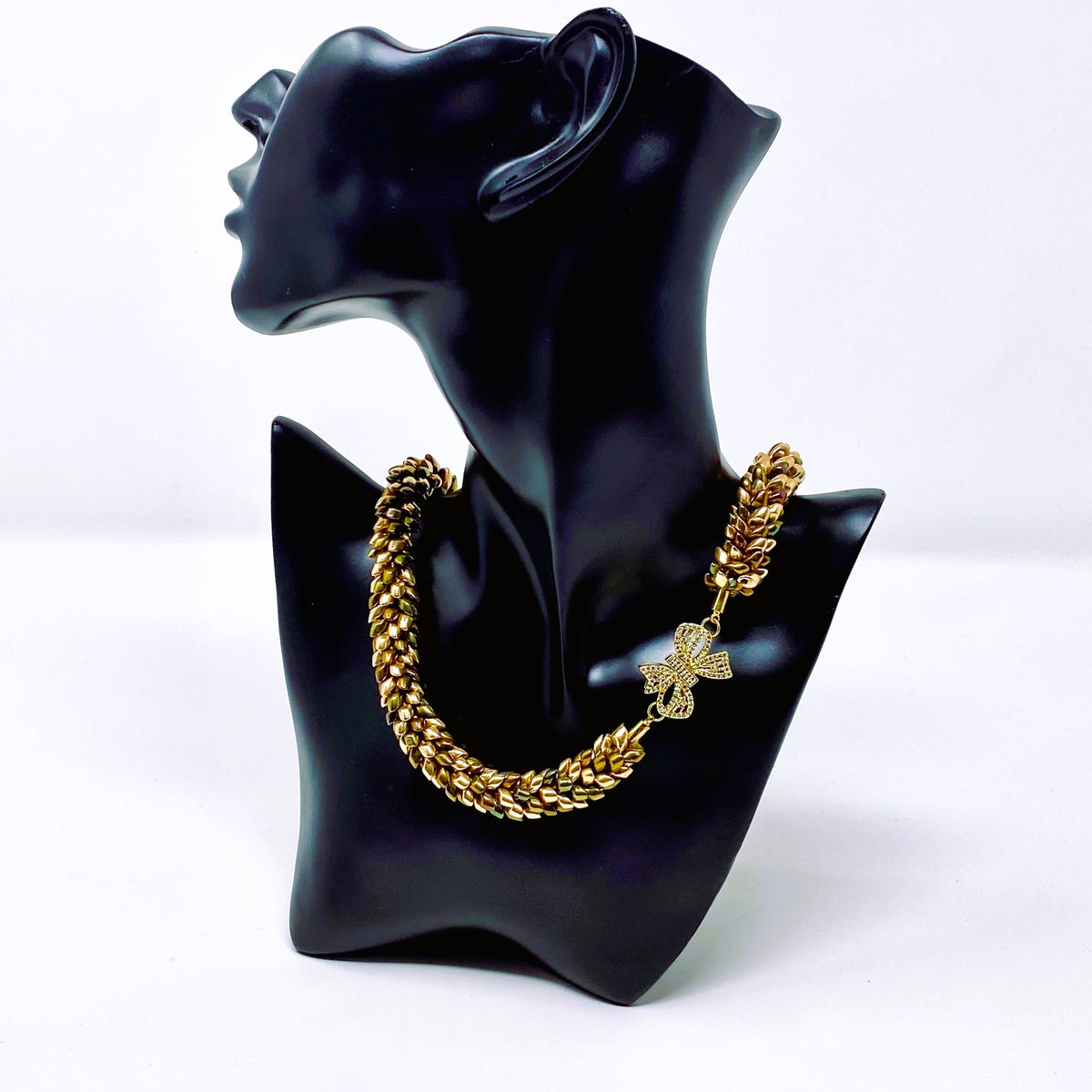 Side view of the Maris magatama beaded collar necklace in champagne, olive and bronze on a black display bust - Lodorfo