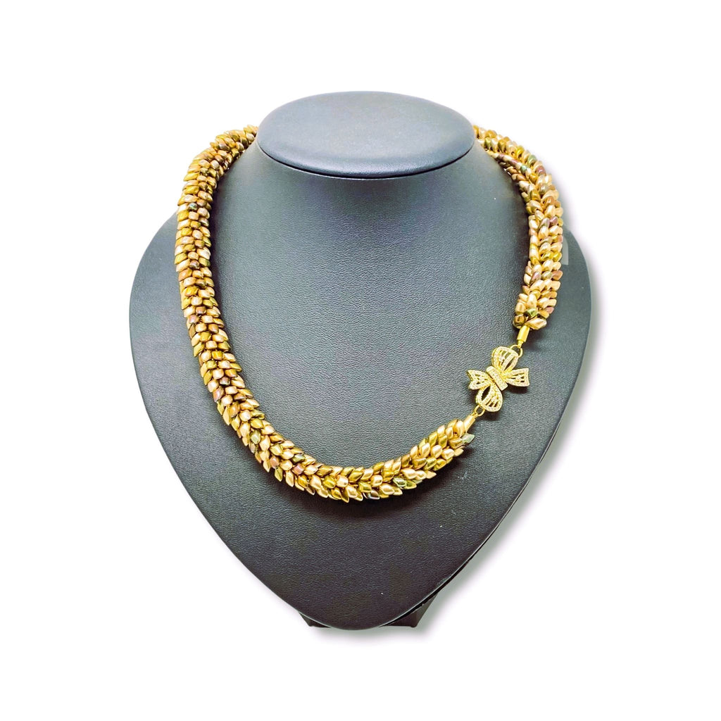 The Maris magatama beaded collar necklace in champagne, olive and bronze on a grey display bust, front view - Lodorfo