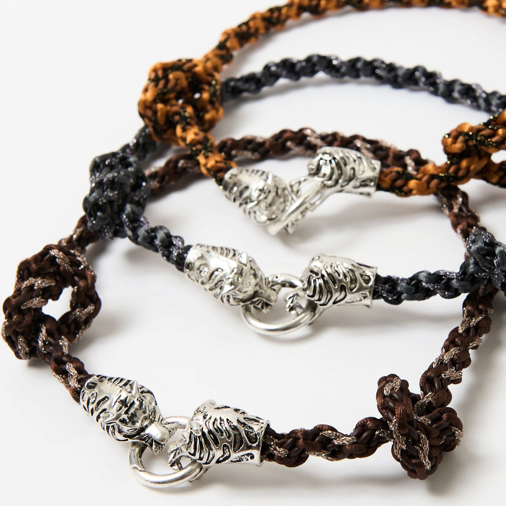 Close-up of the Kaelis silver tiger head clasps on the stacked burnt orange, black and chestnut brown braids - Lodorfo