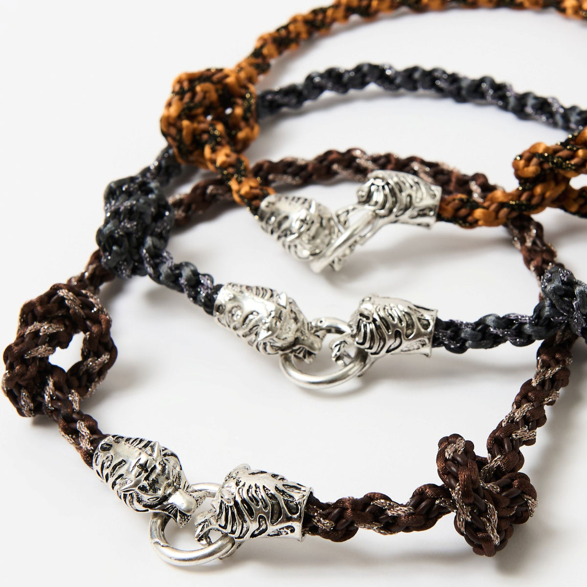 Close-up of the Kaelis silver tiger head clasps on the stacked burnt orange, black and chestnut brown braids - Lodorfo