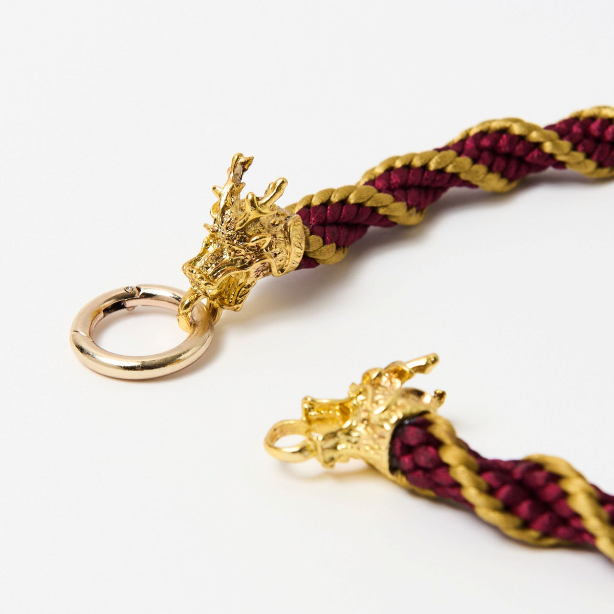 Close-up of the Drakon dragon head clasp and rose gold ring on crimson red and gold braided cord - Lodorfo