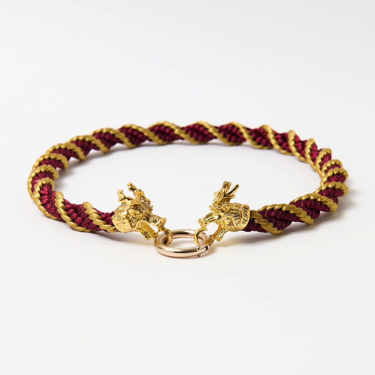 Angled view of the Drakon crimson red and gold braided necklace with two dragon heads joined by a rose gold ring - Lodorfo