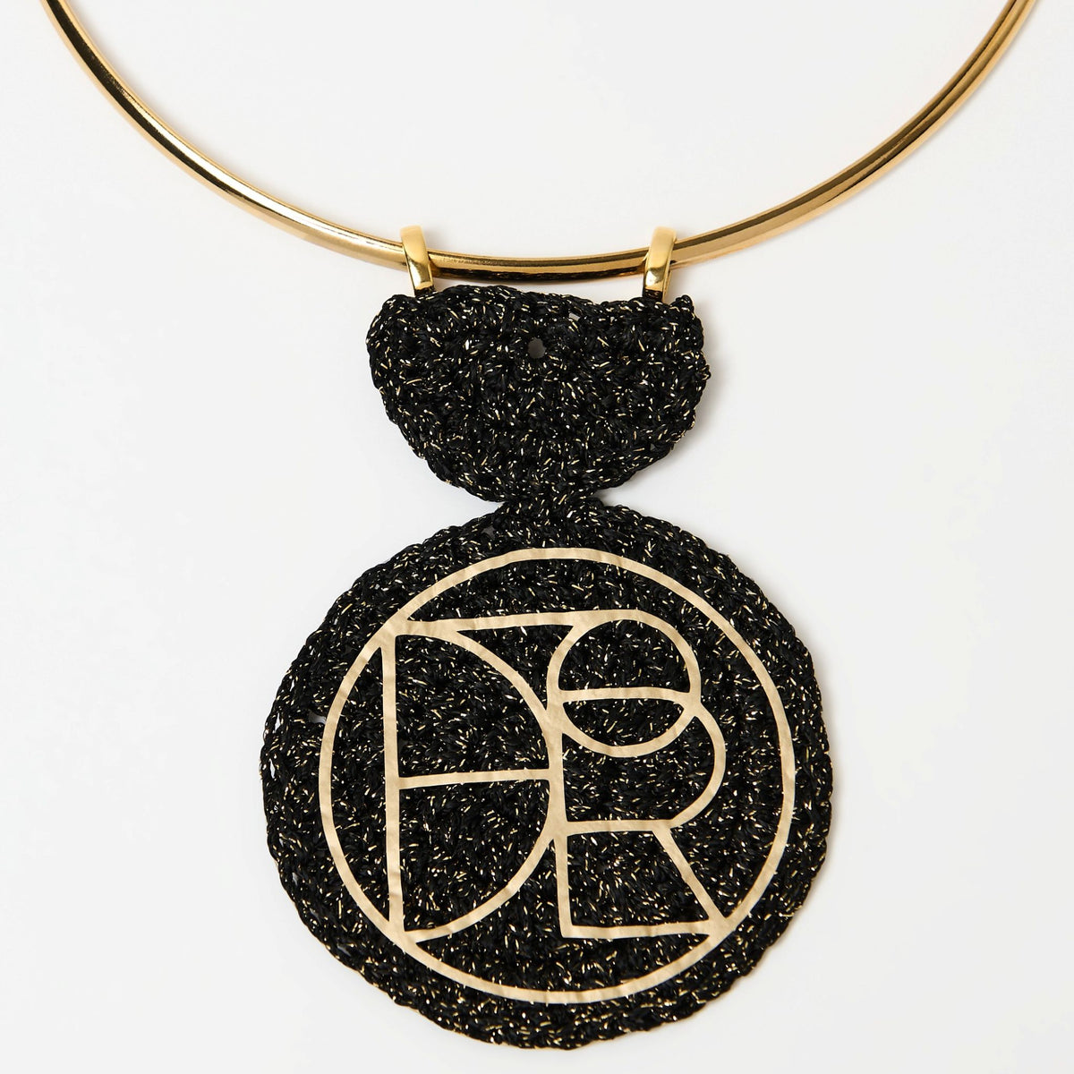 Close-up of the Orion black and gold crochet pendant with its geometric logo cut-out - Lodorfo