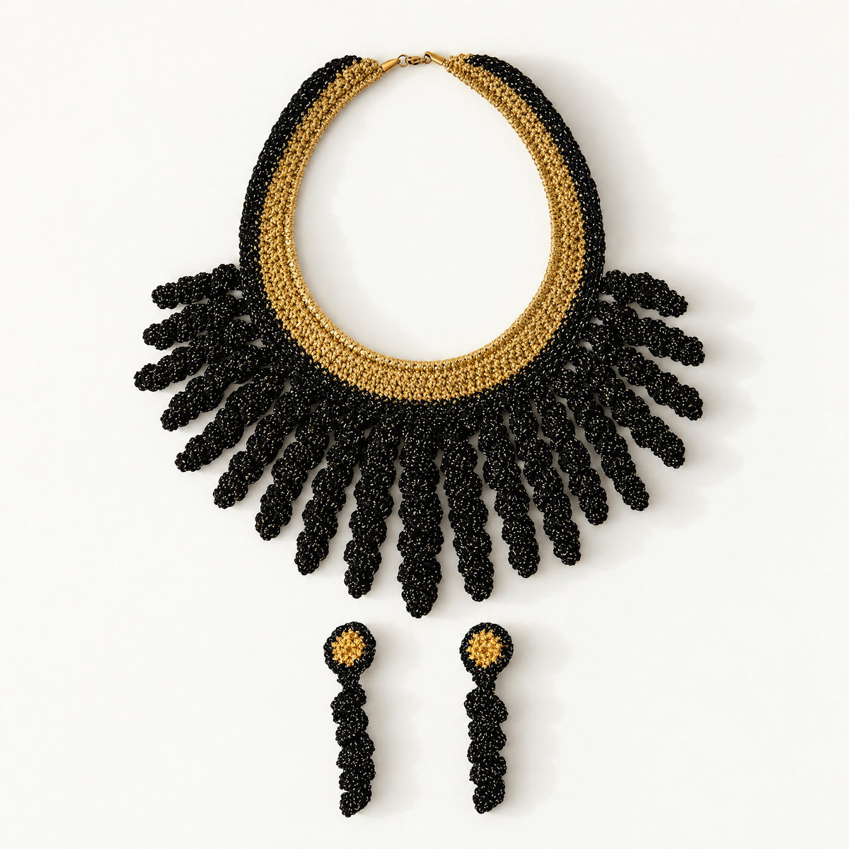 The Vetra Edit set: Vetra black and antique gold crochet collar necklace with Noire gold drop earrings, laid flat - Lodorfo