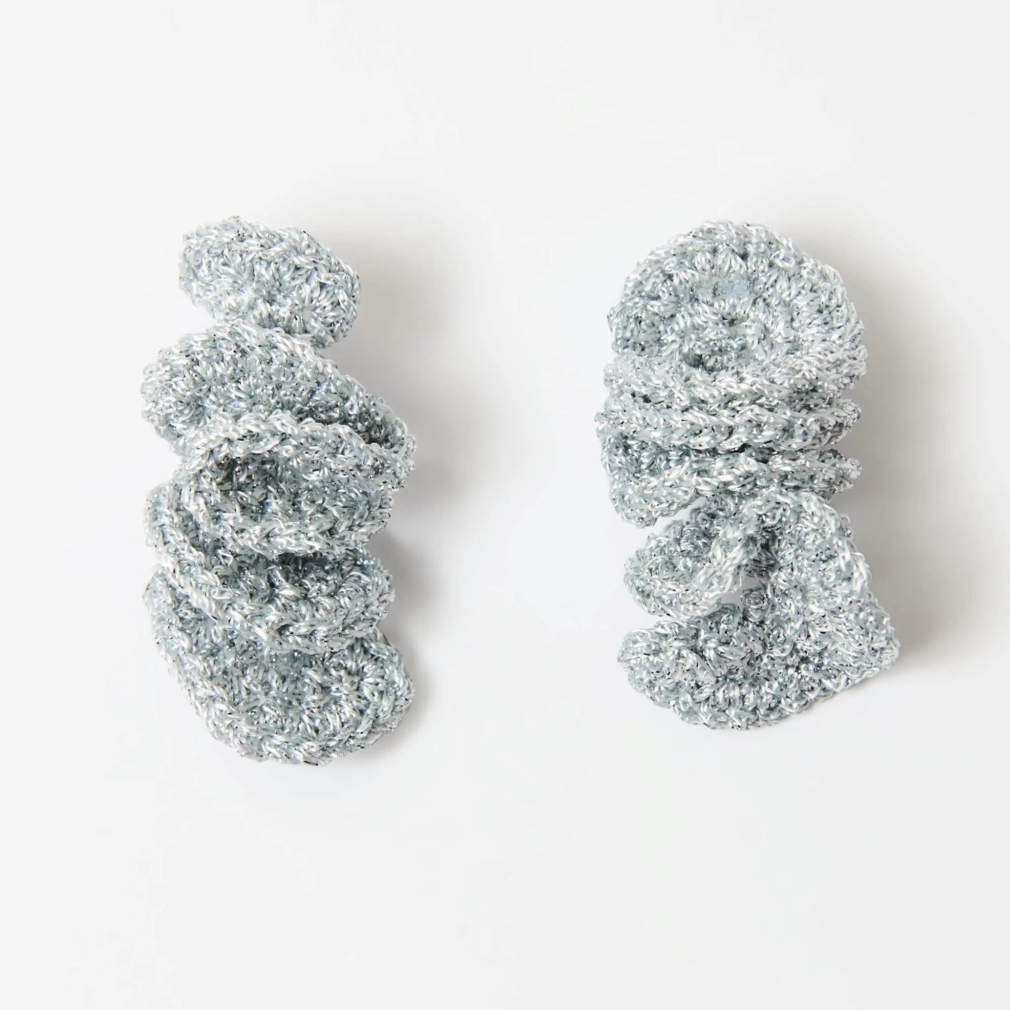 Pair of spiral drop earrings with a sculptural silver knitted design, shown flat against a white background.