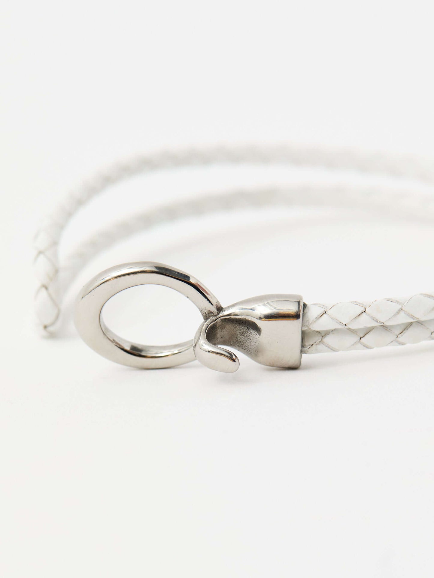 Closeup of white braided leather bracelet with a sleek silver loop and knot clasp, showcasing a modern and minimalist style.
