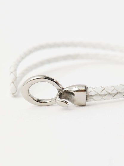 Closeup of white braided leather bracelet with a sleek silver loop and knot clasp, showcasing a modern and minimalist style.