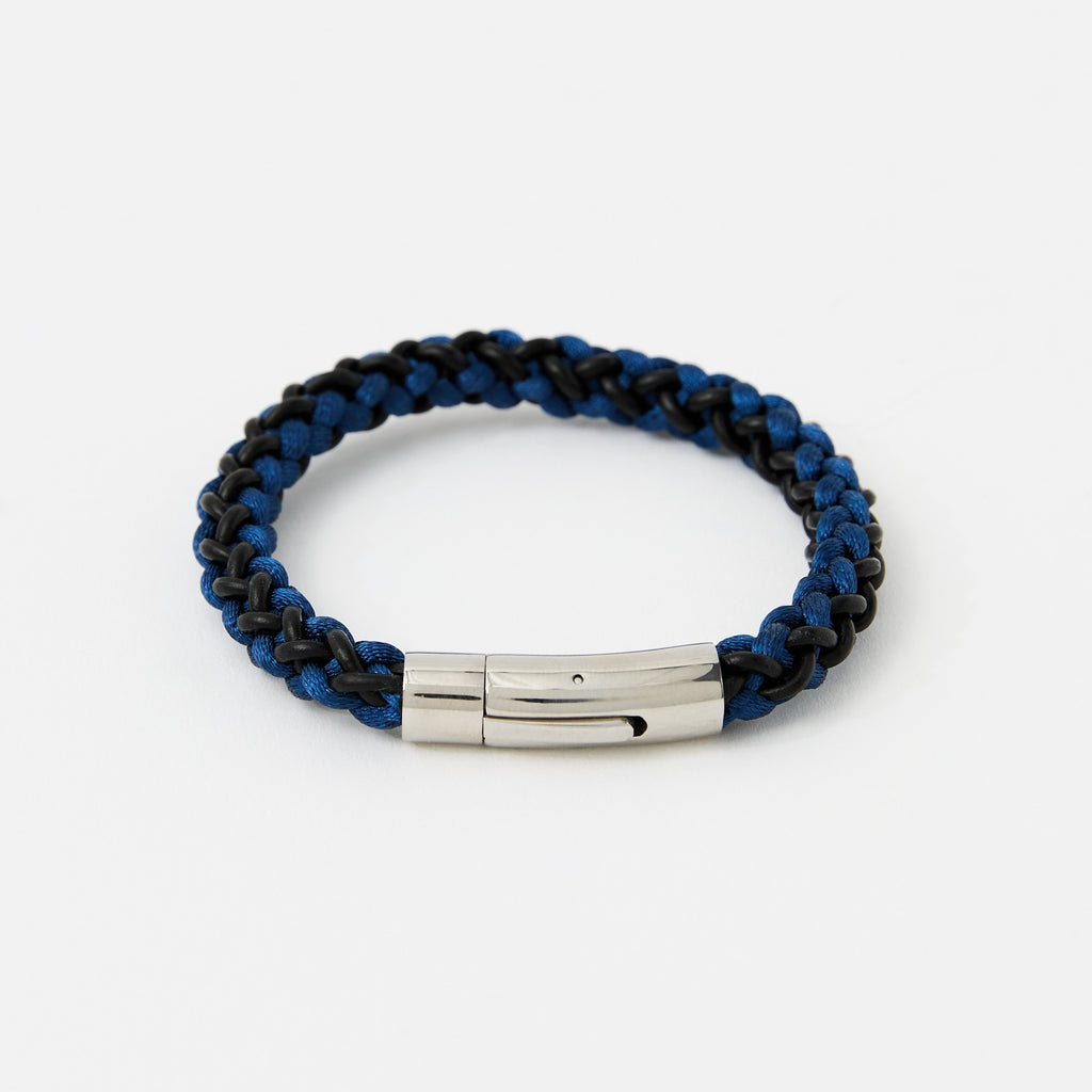 Blue and black braided bracelet with a silver tag on a white background