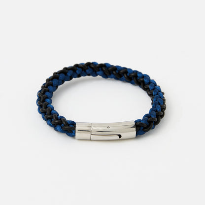 Blue and black braided bracelet with a silver tag on a white background