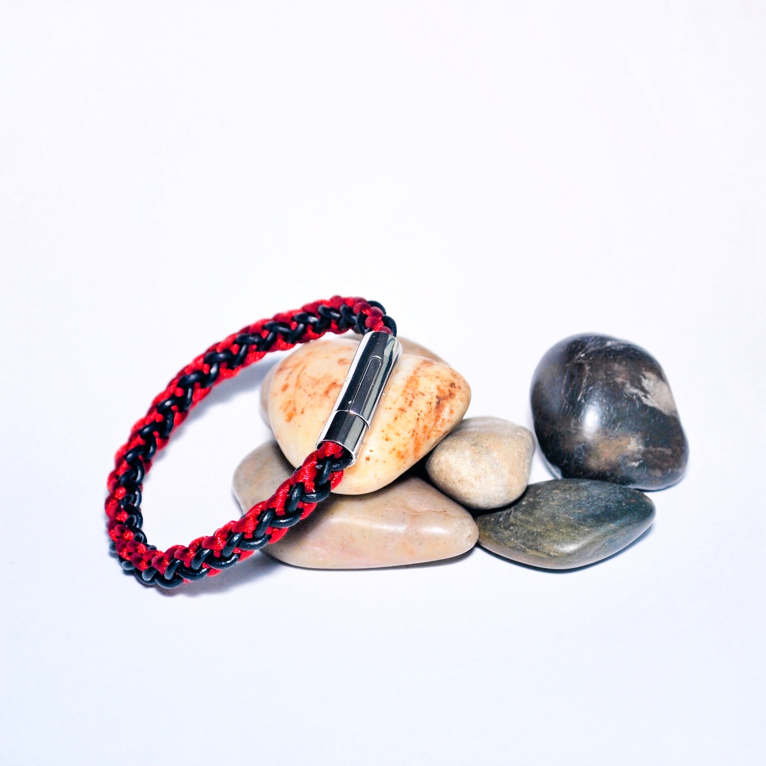 Bracelet with red and black pattern on stones against a white background