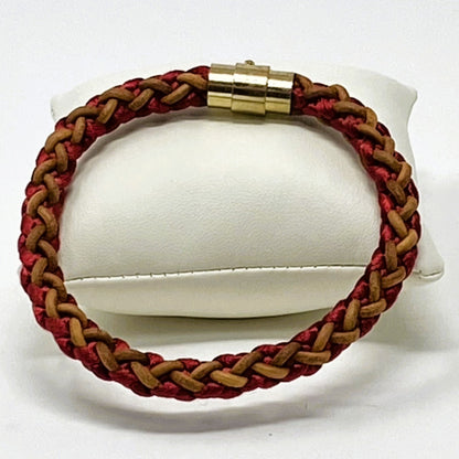 Men’s braided leather bracelet in red and brown with polished gold clasp, elegantly presented on a white display cushion — handcrafted accessory for casual and smart styling.