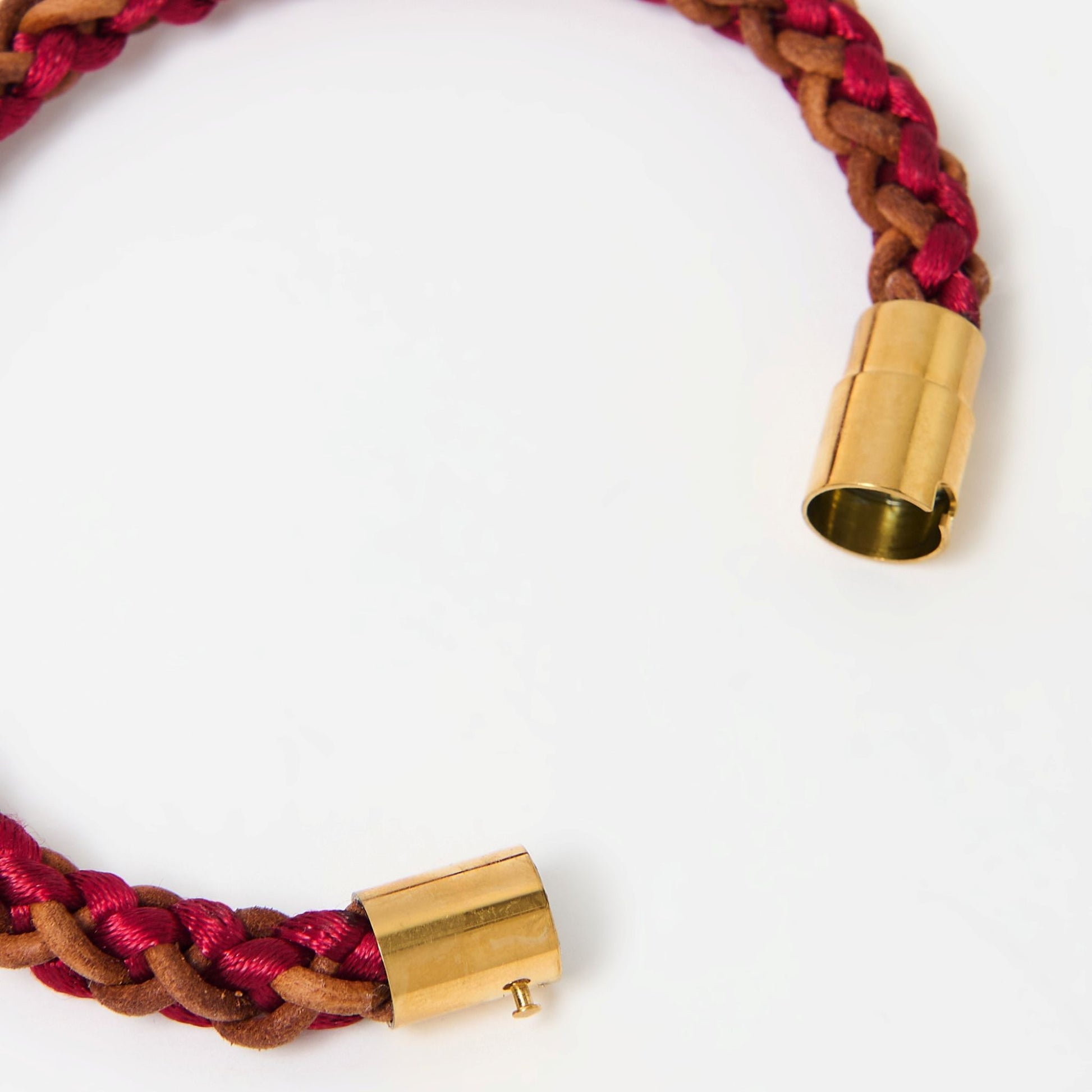 Close-up of artisan-crafted men’s bracelet with red and brown braided leather and polished gold magnetic clasp — modern accessory with timeless appeal.