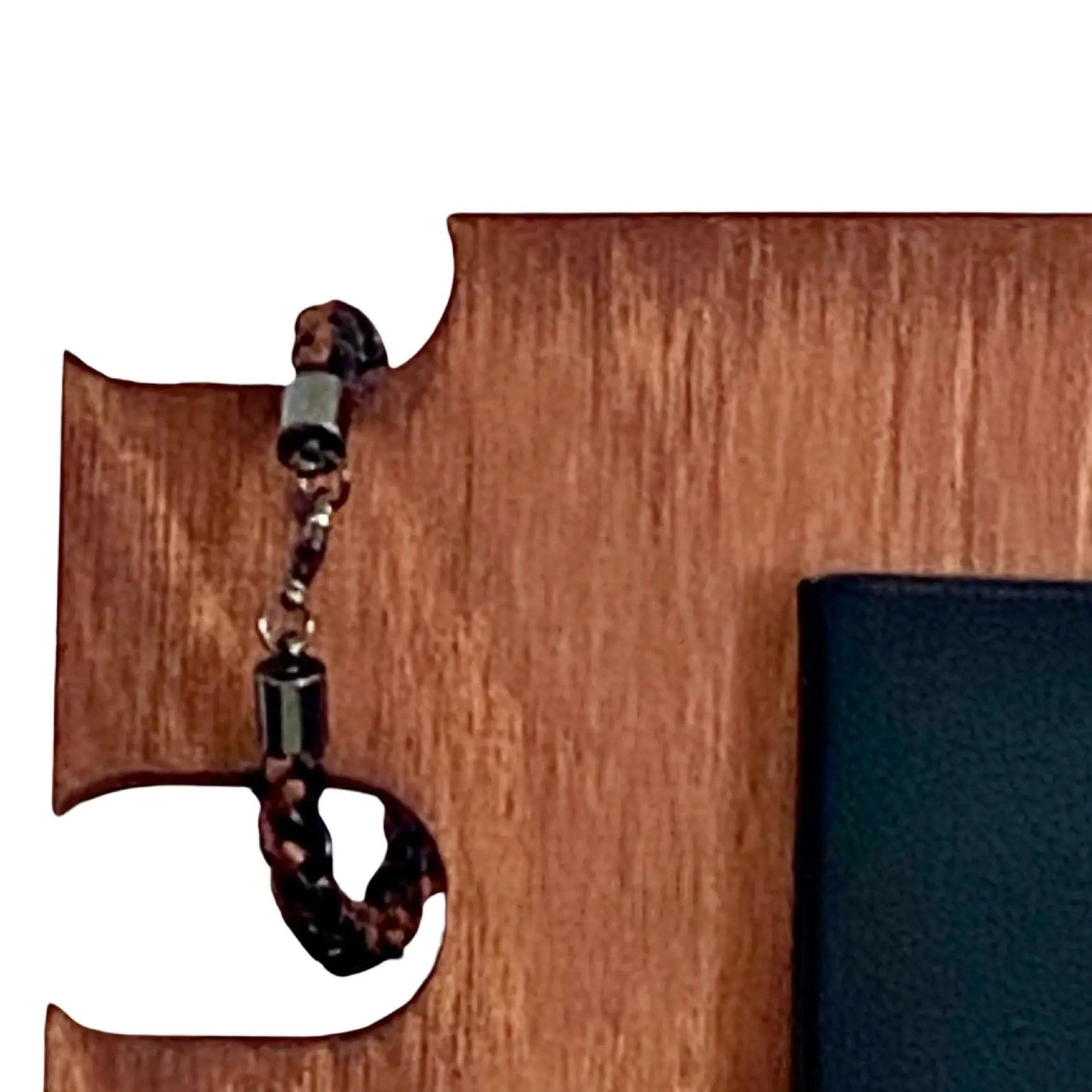 Close-up of brown braided leather bracelet with sleek gunmetal clasp, elegantly styled on a wood organizer — rugged yet refined men’s accessory for everyday use.