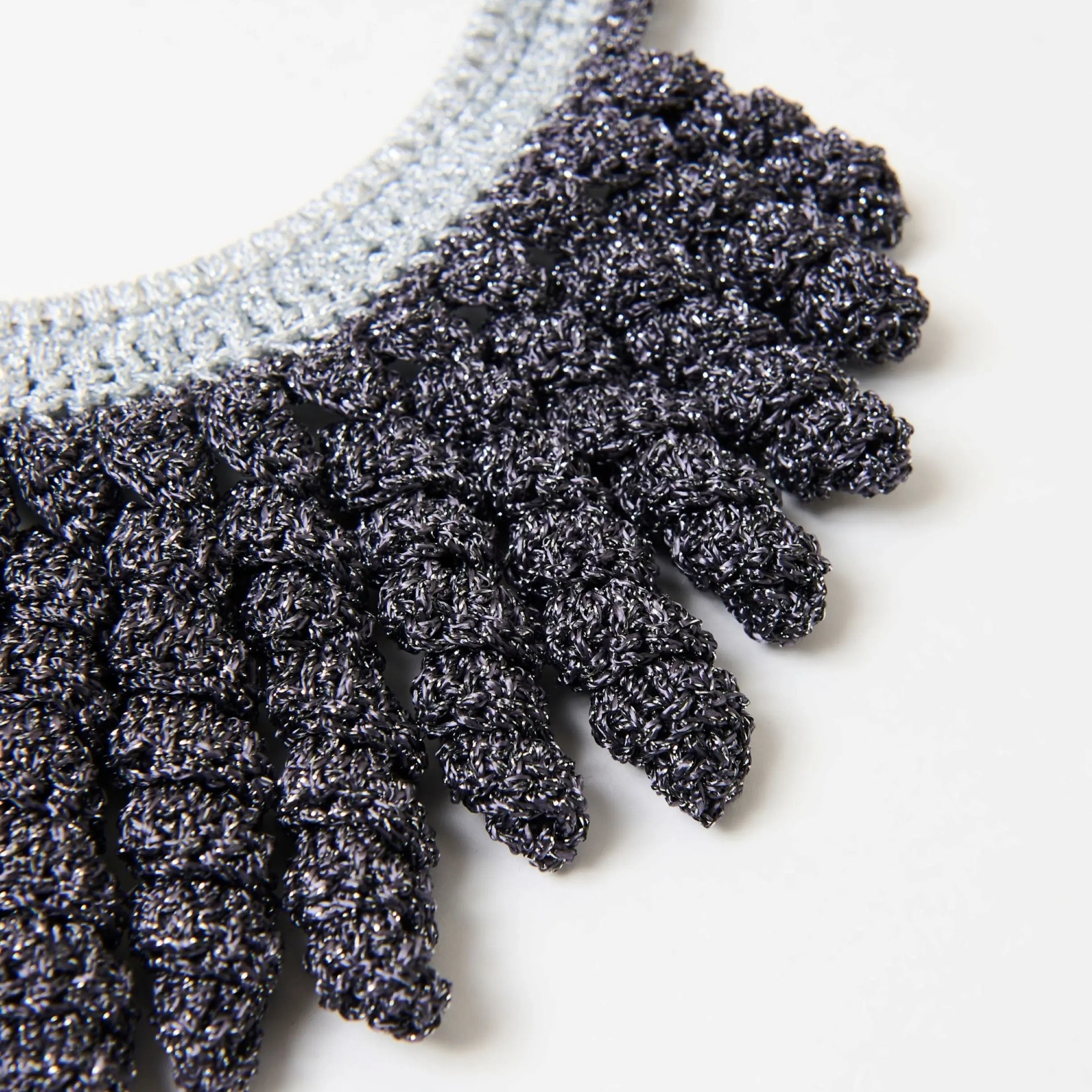 Close-up of handmade necklace in shimmering charcoal grey and silver, showcasing the textured spiral fringe and intricate stitching.