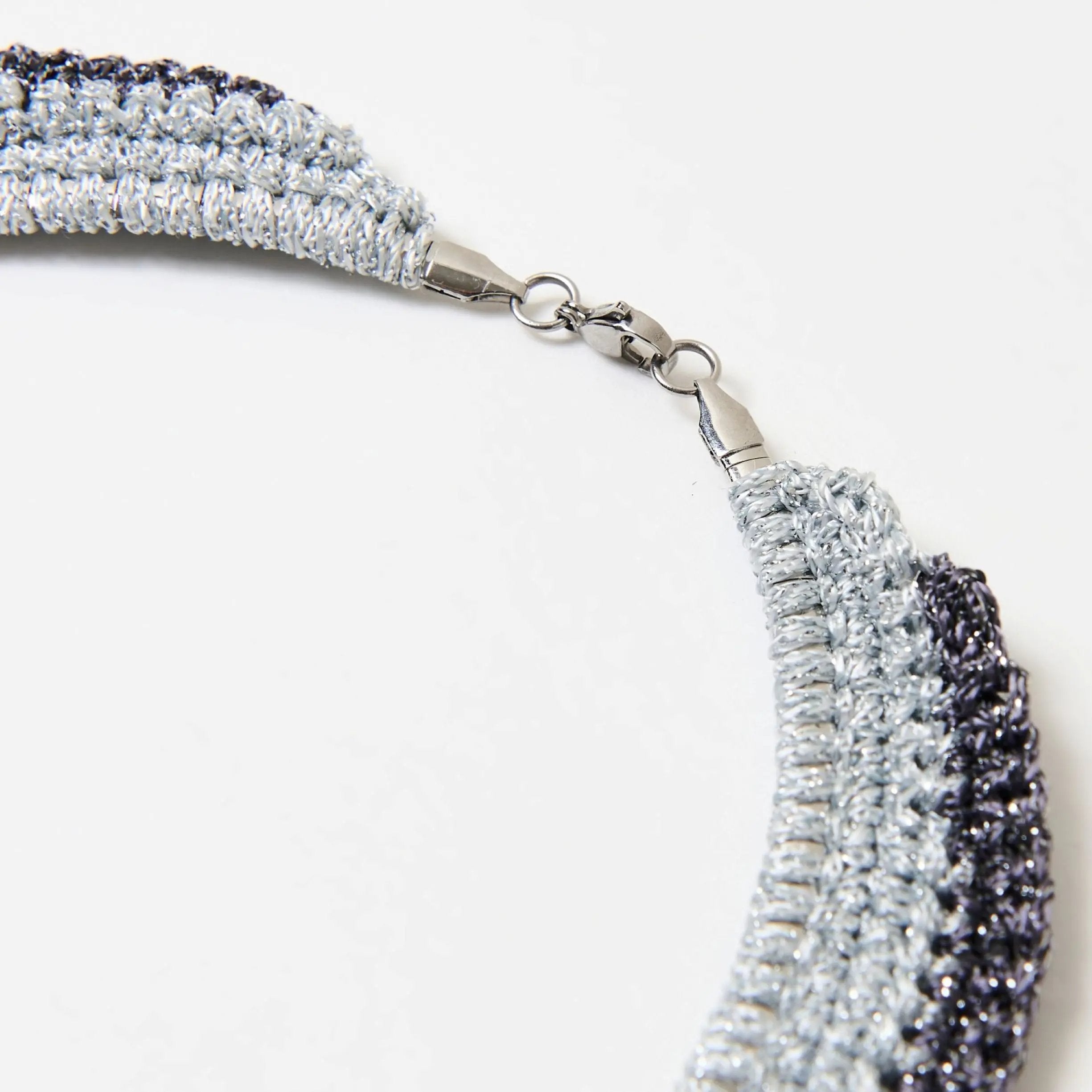 Detailed view of the lobster clasp fastening on a metallic silver and grey handmade statement necklace.