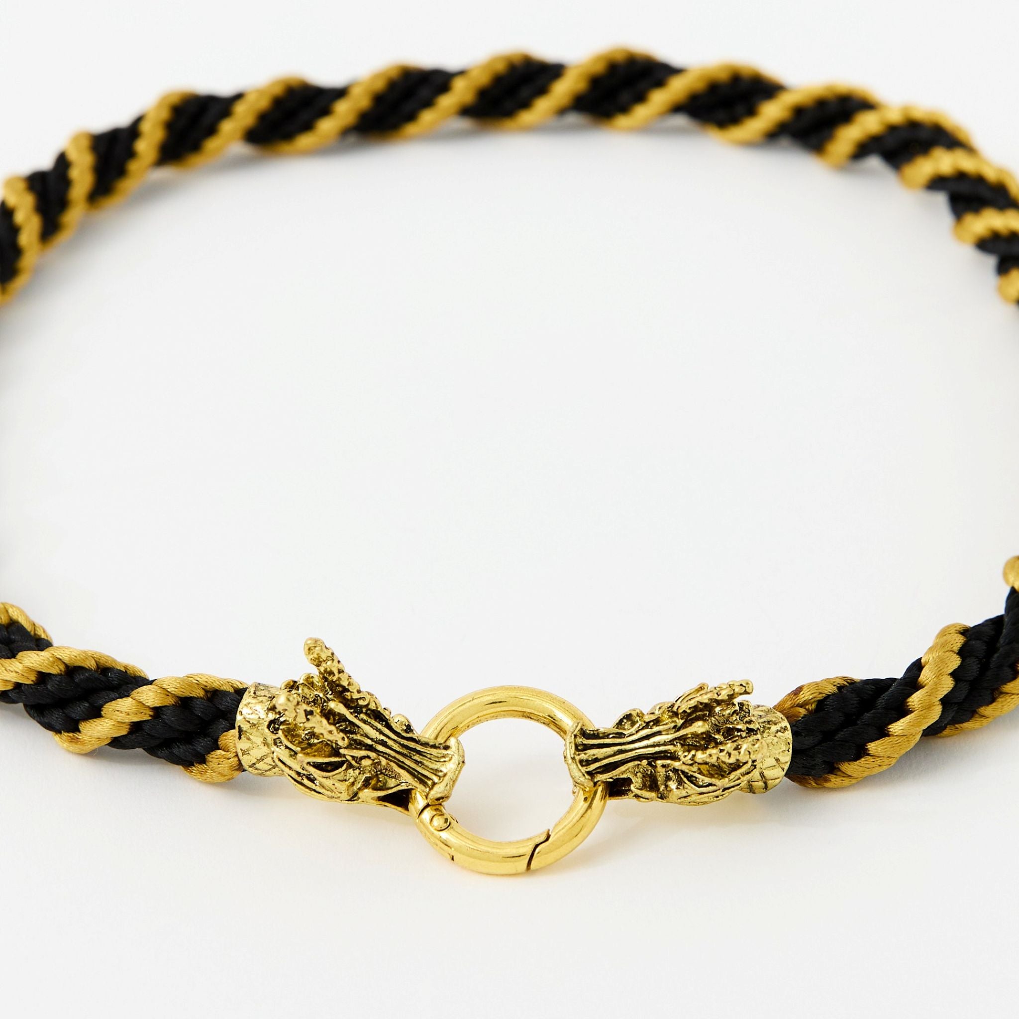 Handmade black and gold satin cord necklace featuring ornate gold dragon head clasp, laid in a circular shape on a white background.