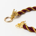 Close-up of gold dragon head clasp on red satin necklace