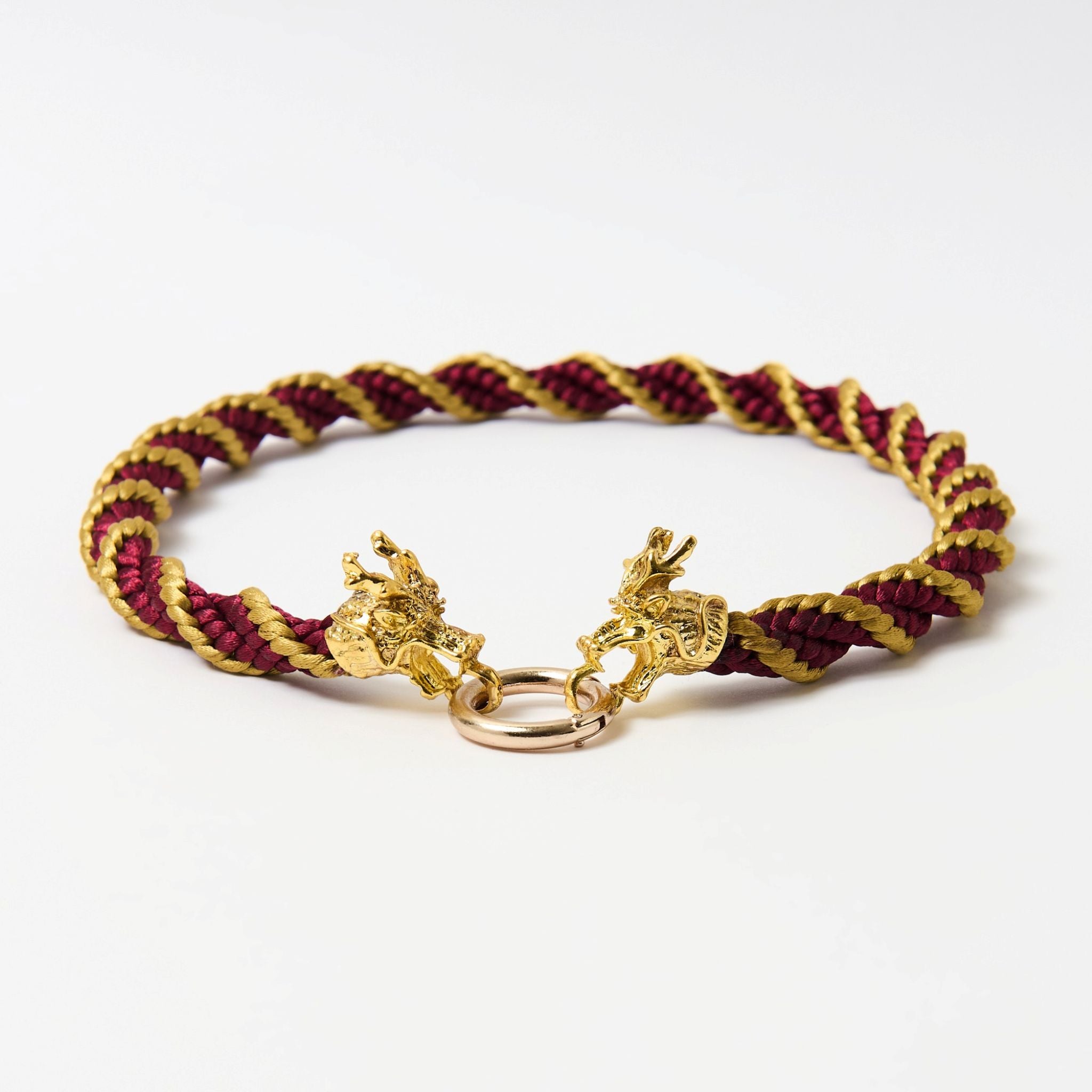 Handmade spiral red and gold satin cord necklace with ornate dragon head clasp, arranged in a semi-circle on a white surface.