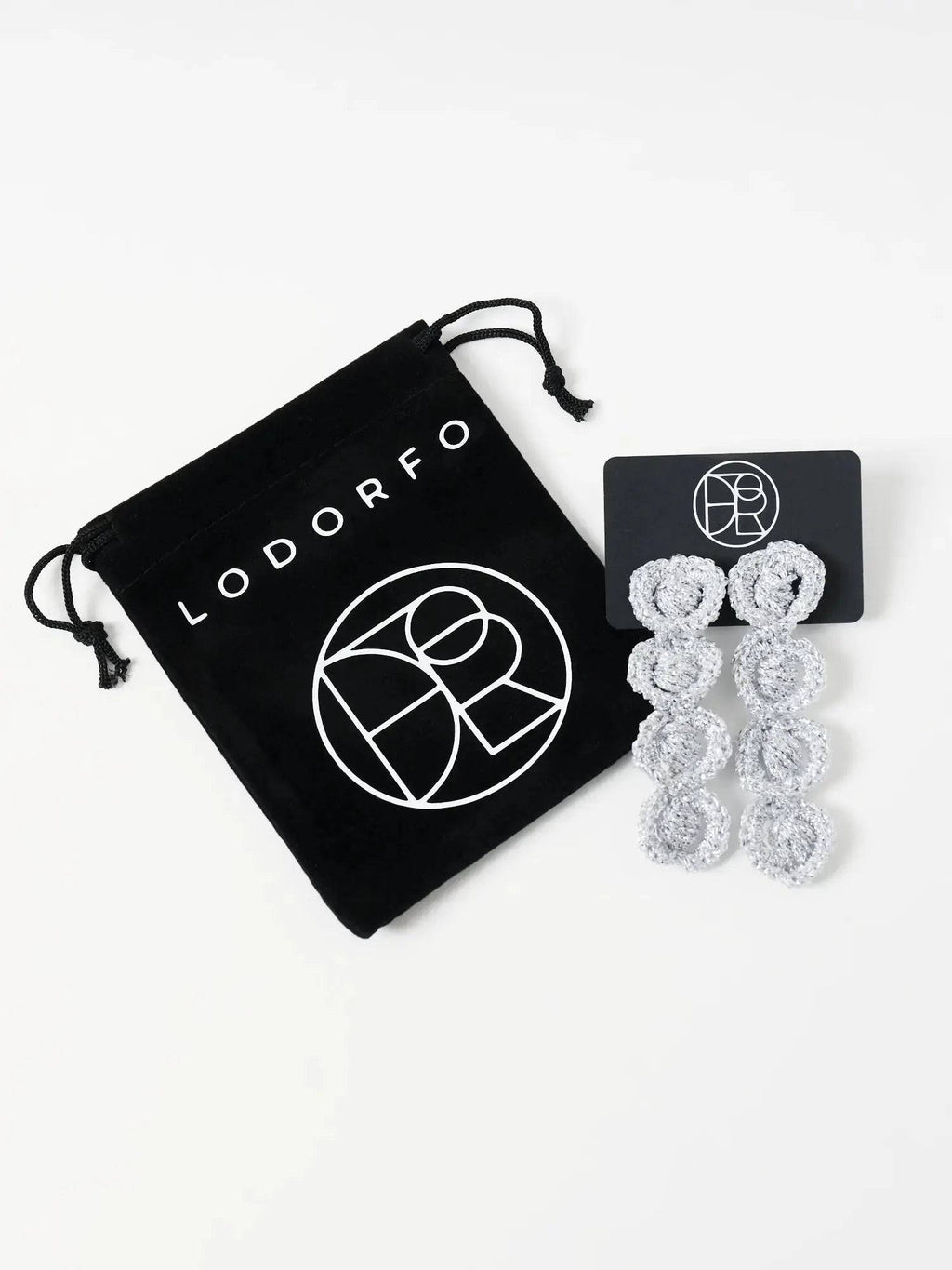 The Arlo sculptural loop earrings, pebble grey long shown on an earring card next to velvet pouch — Lodorfo